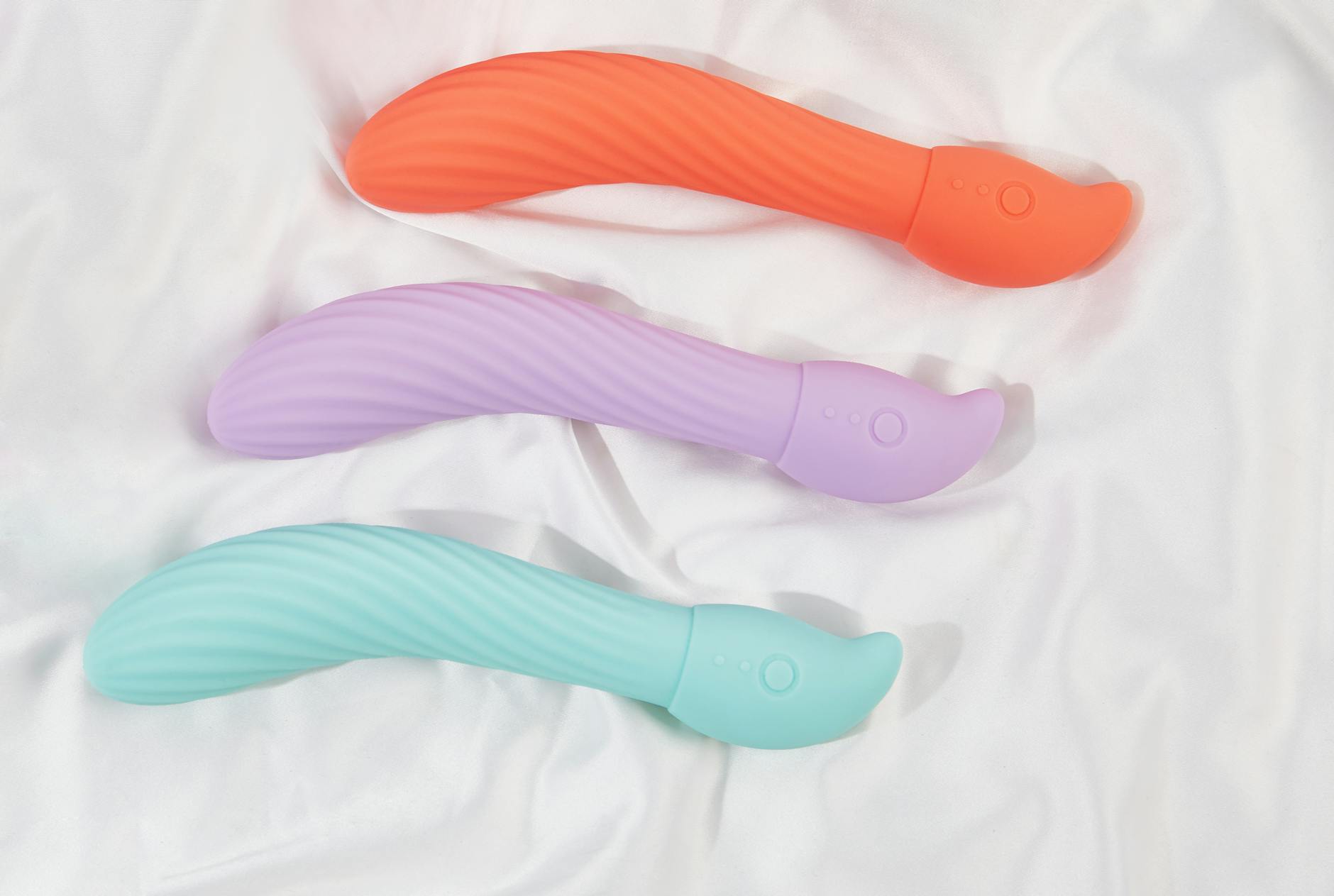 Three colorful vibrators arranged on white fabric, highlighting smooth texture and design