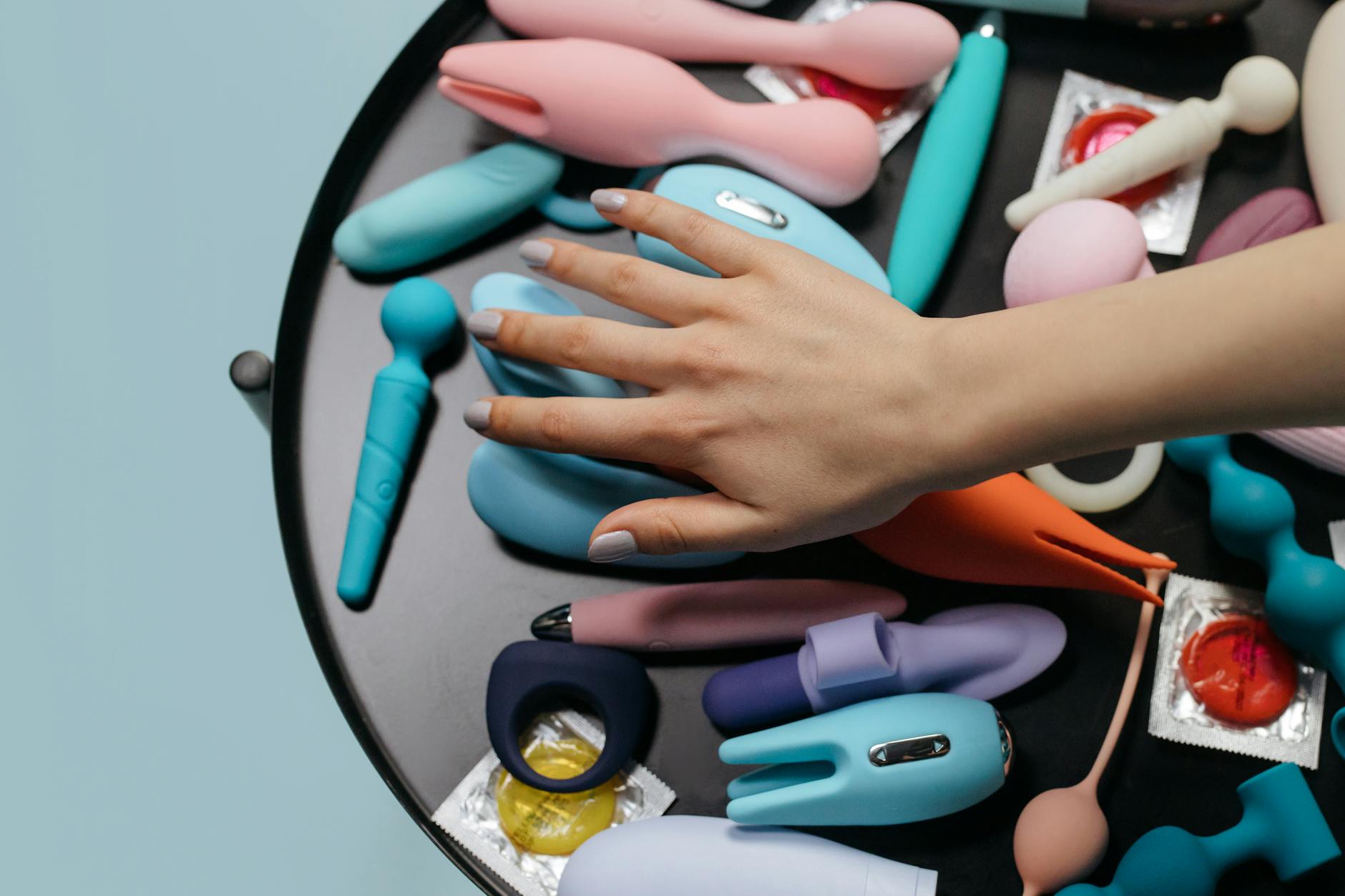 Close-up of hands holding a personal vibrator against a knitted sweater, representing gentle self-care and healing