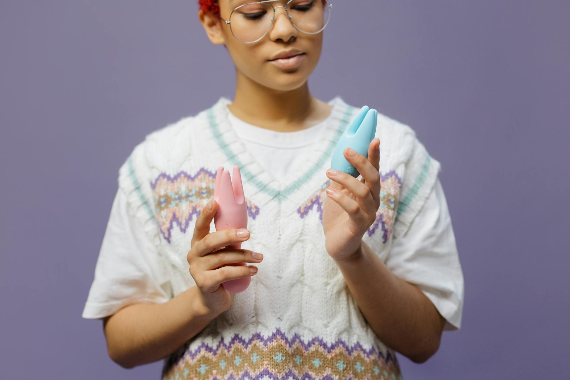 Woman holding a vibrator in a contemplative, peaceful state near her bed.